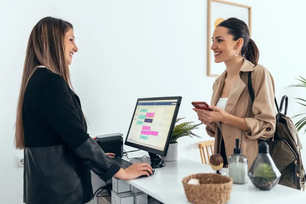 A client checks out at the salon reception desk, representing the feeling of control and confidence that comes with knowledge.