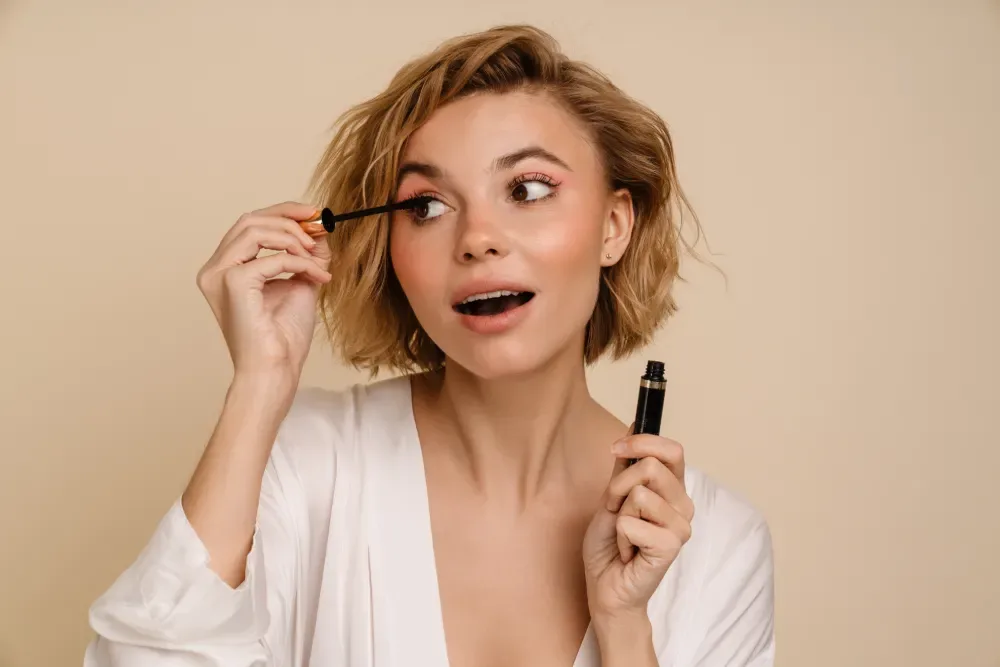 A confident woman applies mascara, symbolizing the beautiful look achieved by trusting professionals over myths.