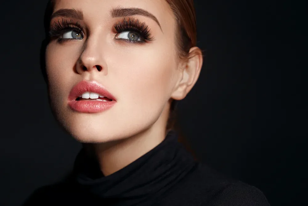 A woman with a bold, dramatic style of eyelash extensions, illustrating the wide range of customizable looks available.