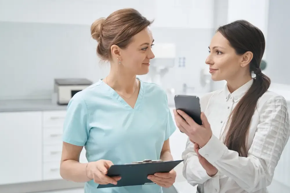 A client shows her phone to a salon professional to review eyelash extension prices in Jacksonville, FL.