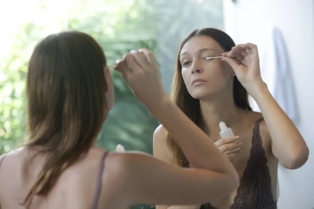 A woman attempts to remove her own lash extensions, illustrating the dangerous myth of at-home removal methods.
