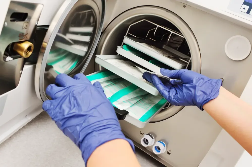 A technician loads packaged instruments into a sterilizer, representing important questions to ask about salon safety and hygiene.