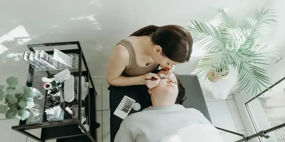A professional applies eyelash extensions in a clean and controlled salon environment, representing the safety of a salon procedure.