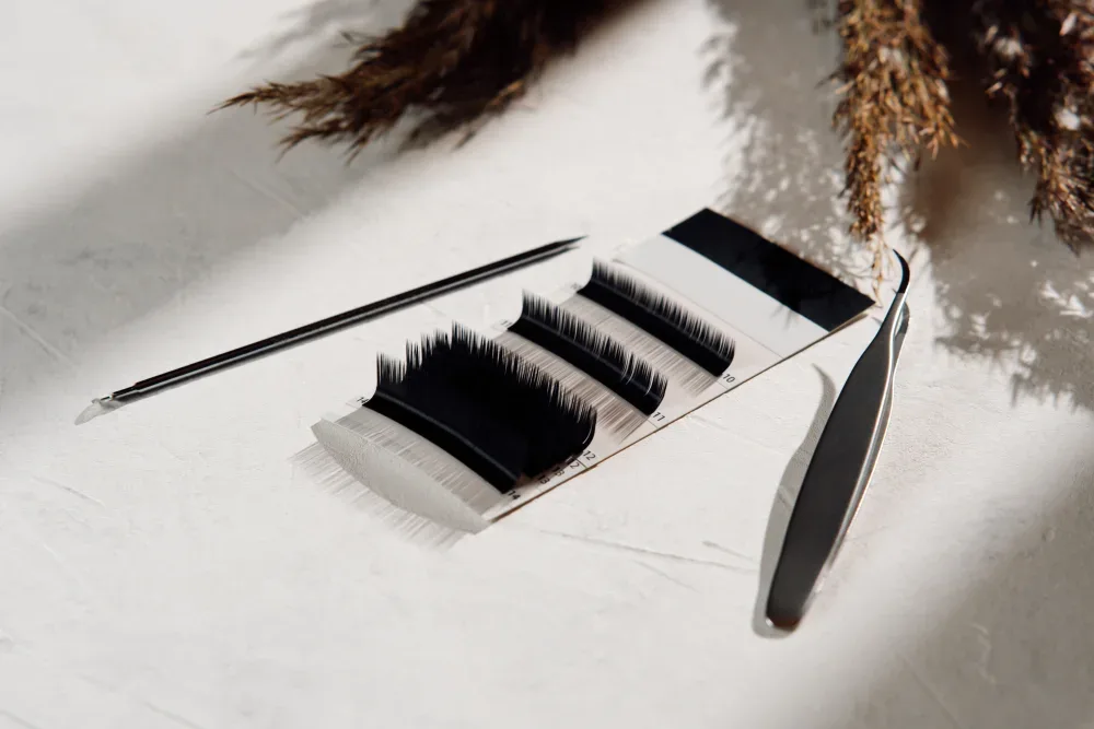 A palette with various eyelash extension strips and professional tools, used for selecting the optimal style and parameters during a consultation.