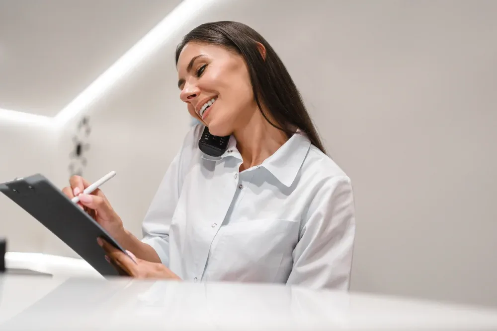 A professional salon receptionist books an appointment while on the phone, representing a salon's welcoming atmosphere and clear policies.