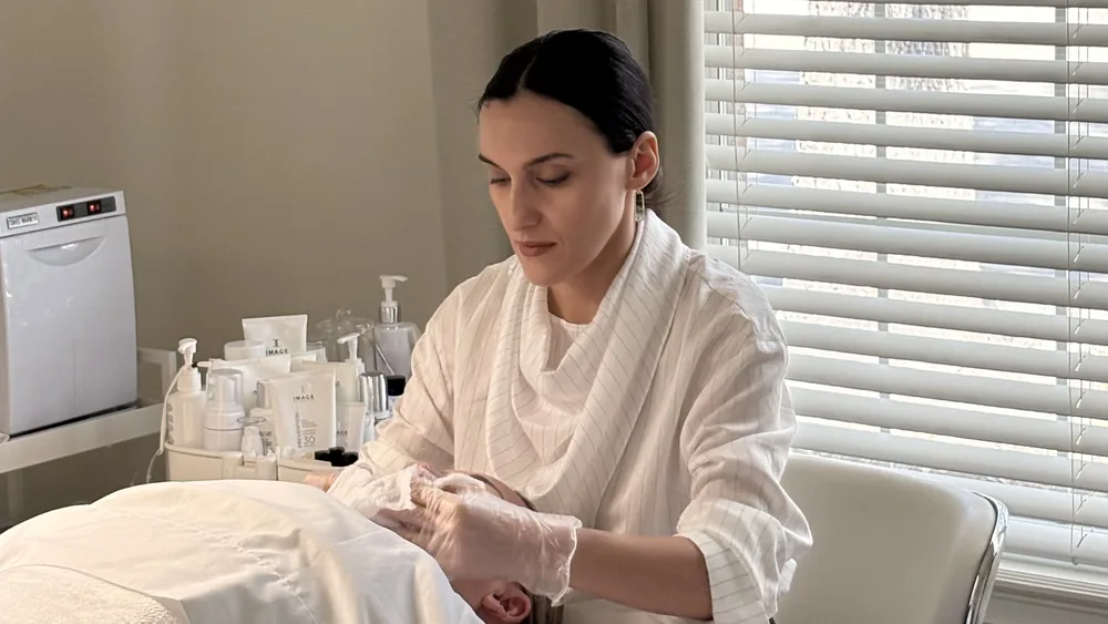 Esthetician performing a facial massage in the ANNAZUR treatment room