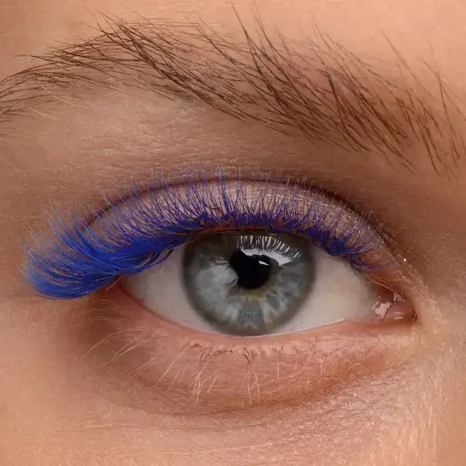 Woman wearing bold blue lash extensions with wet effect glossy finish, creating dramatic mega volume expression style